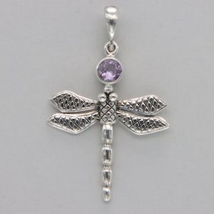 May include: Silver dragonfly pendant with a purple gemstone in the center. The dragonfly's wings are detailed with a textured pattern.