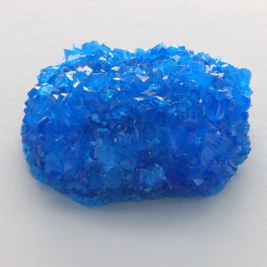May include: A cluster of bright blue crystals, resembling a rock formation. The crystals are translucent and have a slightly iridescent sheen.