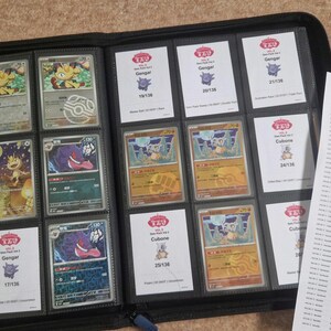 Pode incluir: Um fich&aacute;rio preto cheio de cartas colecion&aacute;veis Pok&eacute;mon, cada uma em mangas individuais. As cartas apresentam v&aacute;rios personagens Pok&eacute;mon e s&atilde;o exibidas em fileiras. Uma folha impressa com o texto "Gem Pack Vol 3 - Card set" &eacute; vis&iacute;vel.