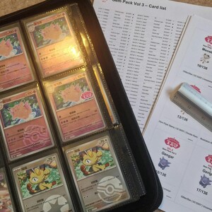 Pode incluir: Um fich&aacute;rio preto cheio de cartas colecion&aacute;veis, com imagens de Clefable e outros personagens. Acompanhando o fich&aacute;rio, h&aacute; folhas impressas com listas de cartas e etiquetas, juntamente com uma r&eacute;gua.