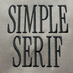 Op de afbeelding: Close-up van een grijze stof met de woorden "SIMPLE SERIF" geborduurd in donkergrijs garen. De tekst is vetgedrukt, met een schreefletter, en de stof heeft een subtiele geweven textuur.