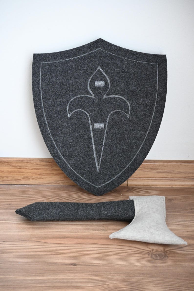 May include: A gray felt shield with a white fleur-de-lis design and a gray felt axe with a white felt blade.