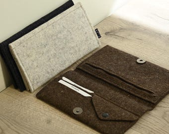 Puede incluir: Carteras de fieltro en varios colores. Las carteras son grises, negras y marrones. Una cartera marrón está abierta, revelando un compartimento con cremallera y ranuras para tarjetas. Cierre de botón.
