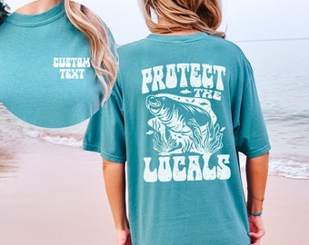Peut inclure: Un t-shirt bleu sarcelle avec un graphique blanc d'un lamantin et le texte "Protégez les locaux".