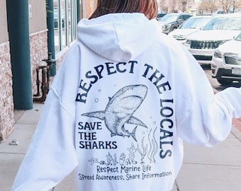 May include: White hoodie with a black graphic print of a shark and the text "Respect the Locals, Save the Sharks, Respect Marine Life, Spread Awareness, Share Information".