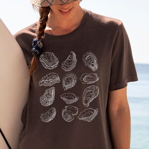 May include: A brown t-shirt with a white graphic print of various oyster shells.