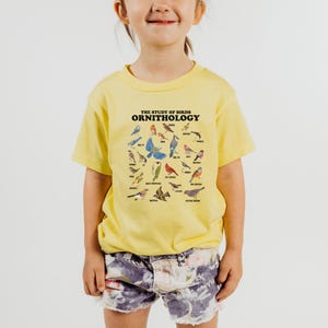 May include: A yellow t-shirt with a graphic of various birds and the text "THE STUDY OF BIRDS ORNITHOLOGY".
