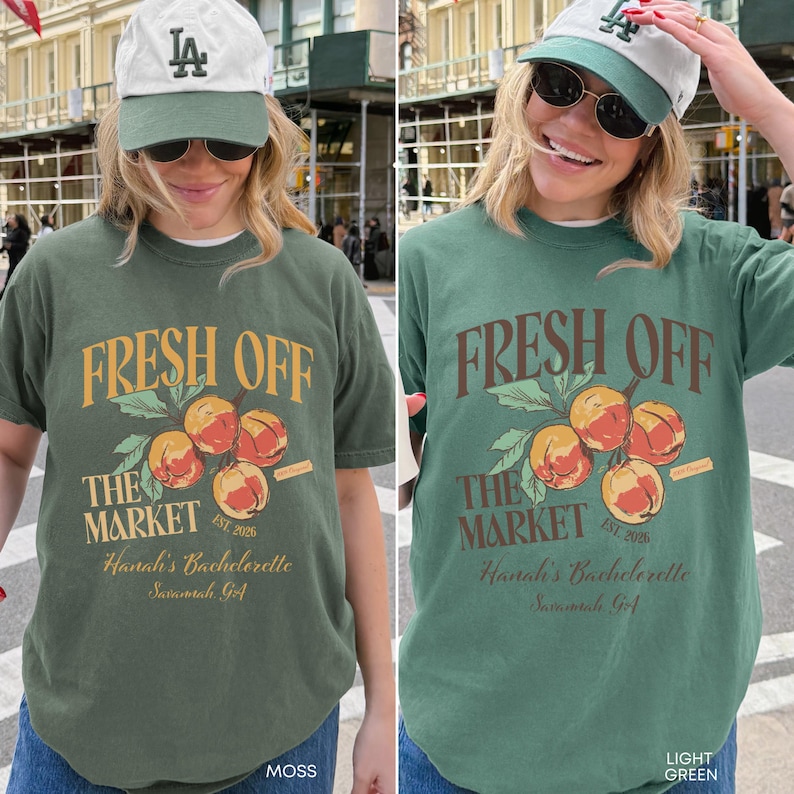 May include: Two t-shirts, one moss green and one light green, each with a graphic design. The design features the text "FRESH OFF THE MARKET" above a cluster of peaches. Below the peaches is the text "Hanah's Bachelorette Savannah, GA".