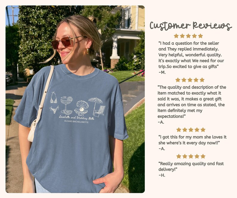 May include: A slate blue short-sleeved t-shirt featuring a white line-art graphic of a bikini, cocktail, pearl in a shell, umbrella, and beach chair. The text reads Seashells and Wedding Bells and OLIVIA'S BACHELORETTE in a cursive and block font.