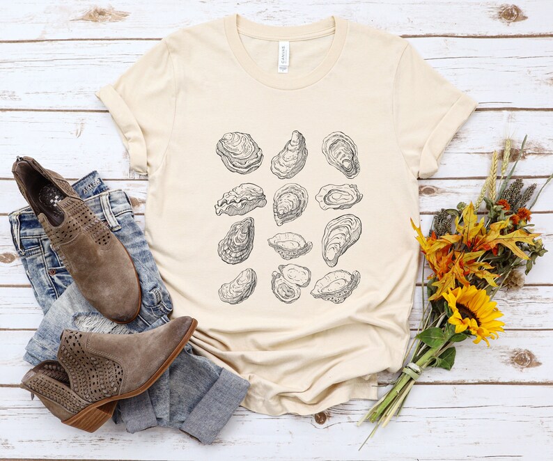 May include: A beige t-shirt with a graphic print of multiple oysters in black and white.