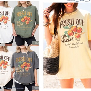 May include: Oversized t-shirts in white, olive green, cream, and charcoal grey. Each shirt features the text "FRESH OFF THE MARKET" with a peach graphic. The text "Katie's Bachelorette Savannah, GA" is also printed on the shirts.