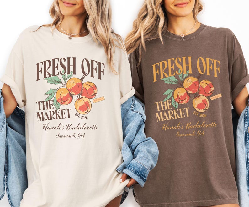 May include: Two t-shirts, one cream and one brown, featuring the text "FRESH OFF THE MARKET" above a peach graphic. The text "Hanah's Bachelorette Savannah GA" is below. The cream shirt has a light blue denim jacket.