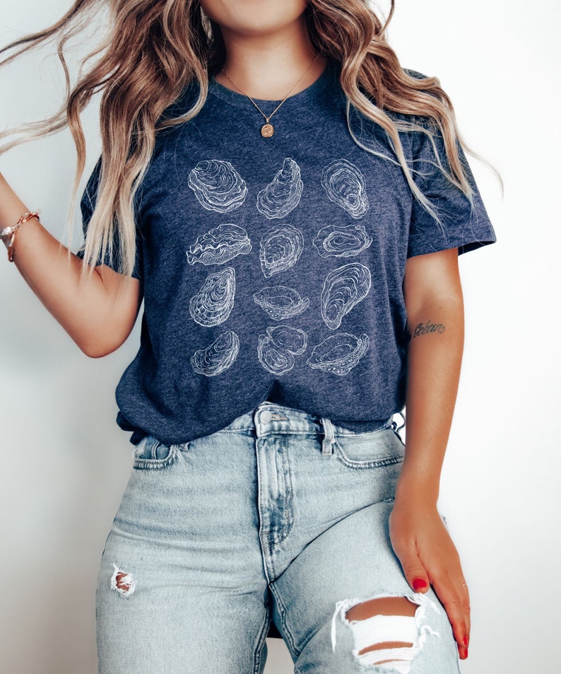 May include: A navy blue t-shirt with a white outline design of multiple oysters. The shirt is made of a soft, comfortable material and has a relaxed fit.