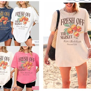 May include: Oversized t-shirts in various colors, including navy, white, and pink, featuring the text "FRESH OFF THE MARKET" with a peach graphic. The shirts are part of a bachelorette collection.