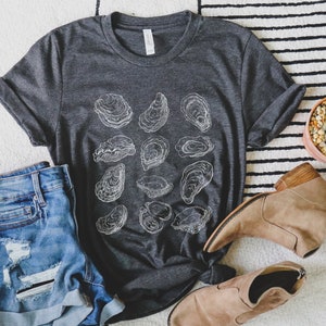 May include: A dark gray t-shirt with a white graphic of oyster shells. The shirt is made of a soft, comfortable material and has a relaxed fit.