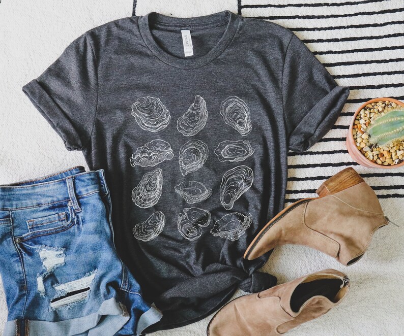 May include: A dark gray t-shirt with a white graphic of oyster shells. The shirt is made of a soft, comfortable material and has a relaxed fit.