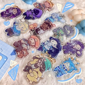 May include: A collection of 11 colorful character keychains featuring various designs. The keychains are made of clear acrylic and feature a variety of characters, including a purple and black character with a crown, a blue and white character with a snowflake, and a green and yellow character with a star. The keychains are perfect for adding a touch of personality to your bag or keys.