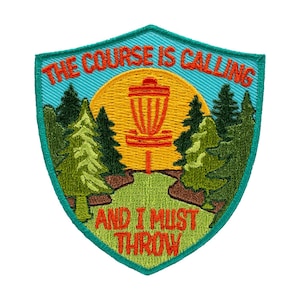 May include: Embroidered patch with a shield shape, featuring a disc golf basket in front of a yellow sun. The text "THE COURSE IS CALLING AND I MUST THROW" is in orange. The patch has a teal border and green trees.