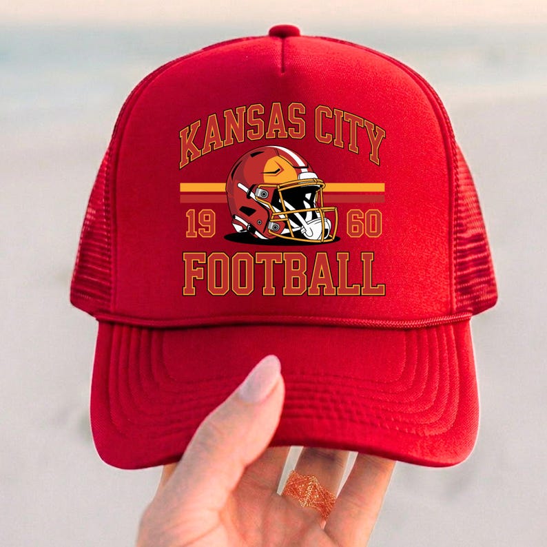 May include: Red trucker hat with the text "Kansas City Football" and a football helmet graphic. The hat includes the years "1960" and has a mesh back.