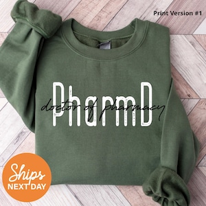 May include: Green sweatshirt with white text that reads "PharmD doctor of pharmacy".