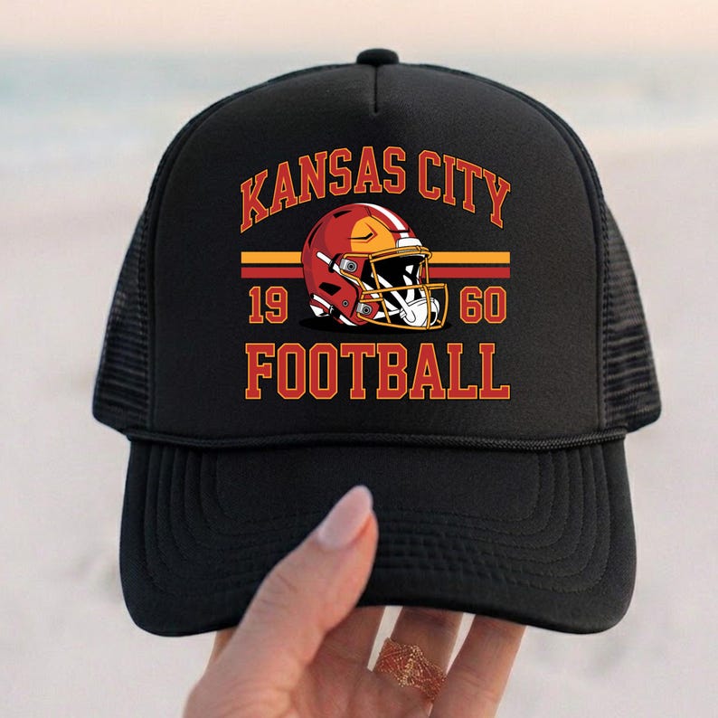 May include: Black trucker hat with the text "KANSAS CITY FOOTBALL" in red and gold, and a football helmet graphic. The hat also displays the numbers "19" and "60".
