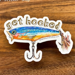 May include: A white sticker with a blue, orange, and yellow fishing lure with the text "get hooked" in gold letters. The lure has a hook and a feather tail.
