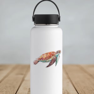 May include: A white stainless steel water bottle with a black lid and a black handle. A colorful watercolor sticker of a sea turtle is on the front of the bottle.