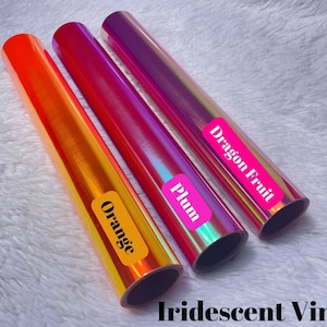 May include: Three rolls of iridescent vinyl in orange, plum, and dragon fruit colors. Each roll has a label with the color name. The text "Iridescent Vinyl" is at the bottom of the image.