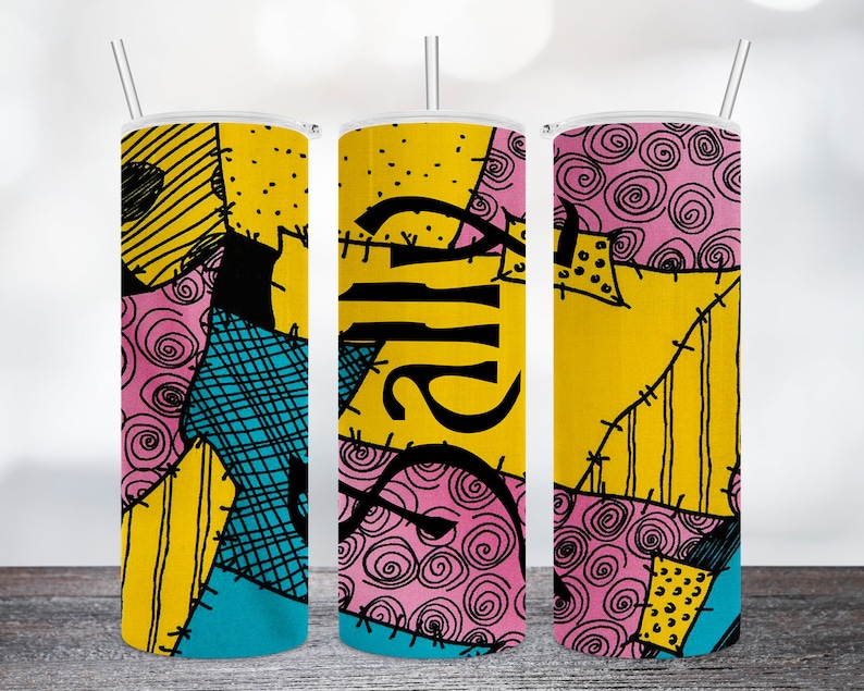 May include: Three stainless steel tumblers with lids and straws. The tumblers are decorated with a patchwork design in shades of yellow, pink, blue, and black. The word "Sally" is written in black on the middle tumbler.