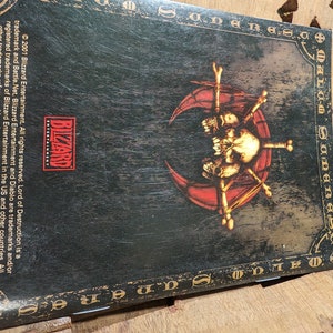 Op de afbeelding: Een zwarte en rode Diablo II Lord of Destruction gamebox met een schedel en gekruiste beenderen logo. De tekst "Diablo II Lord of Destruction" is geschreven in een gotisch lettertype.