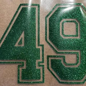 May include: Green glitter iron-on numbers 49 with a white outline. The numbers are in a bold, blocky font.
