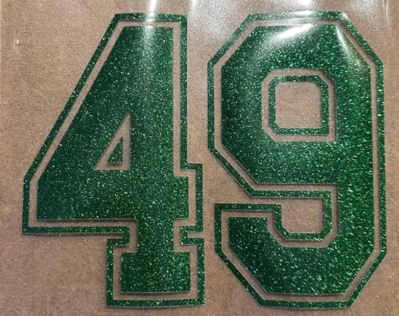 May include: Green glitter iron-on numbers 49 with a white outline. The numbers are in a bold, blocky font.