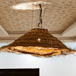 May include: A large, round, woven light fixture hangs from the ceiling. The fixture is made of natural materials and has a light brown color.