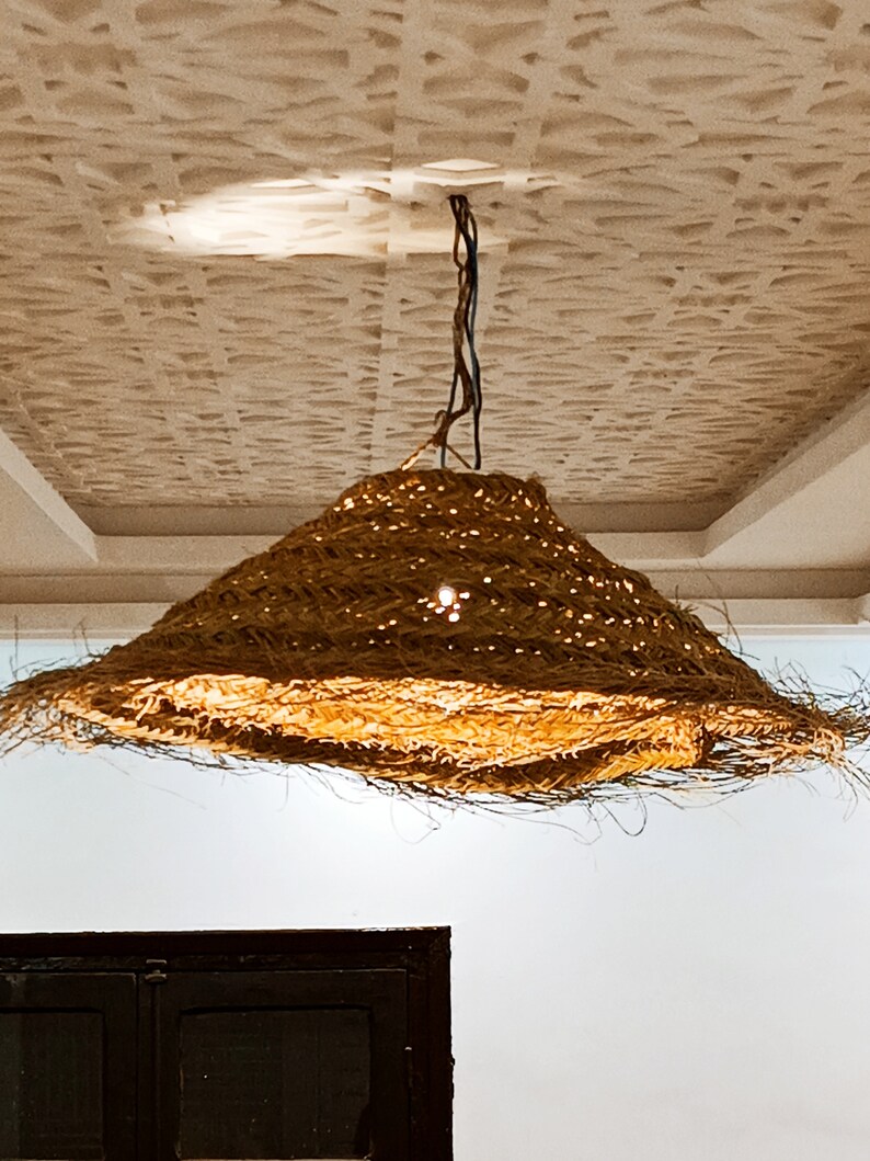 May include: A large, round, woven light fixture hangs from the ceiling. The fixture is made of natural materials and has a light brown color.