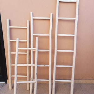 Puede incluir: Cuatro escaleras de madera blanca de diferentes alturas apoyadas en una pared de color melocot&oacute;n. Las escaleras tienen un aspecto r&uacute;stico y natural, perfectas para a&ntilde;adir un toque de estilo farmhouse a cualquier habitaci&oacute;n.