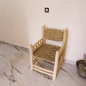 Pode incluir: Uma cadeira de madeira com assento e encosto de vime. A cadeira &eacute; feita de madeira natural e tem um design simples e r&uacute;stico.