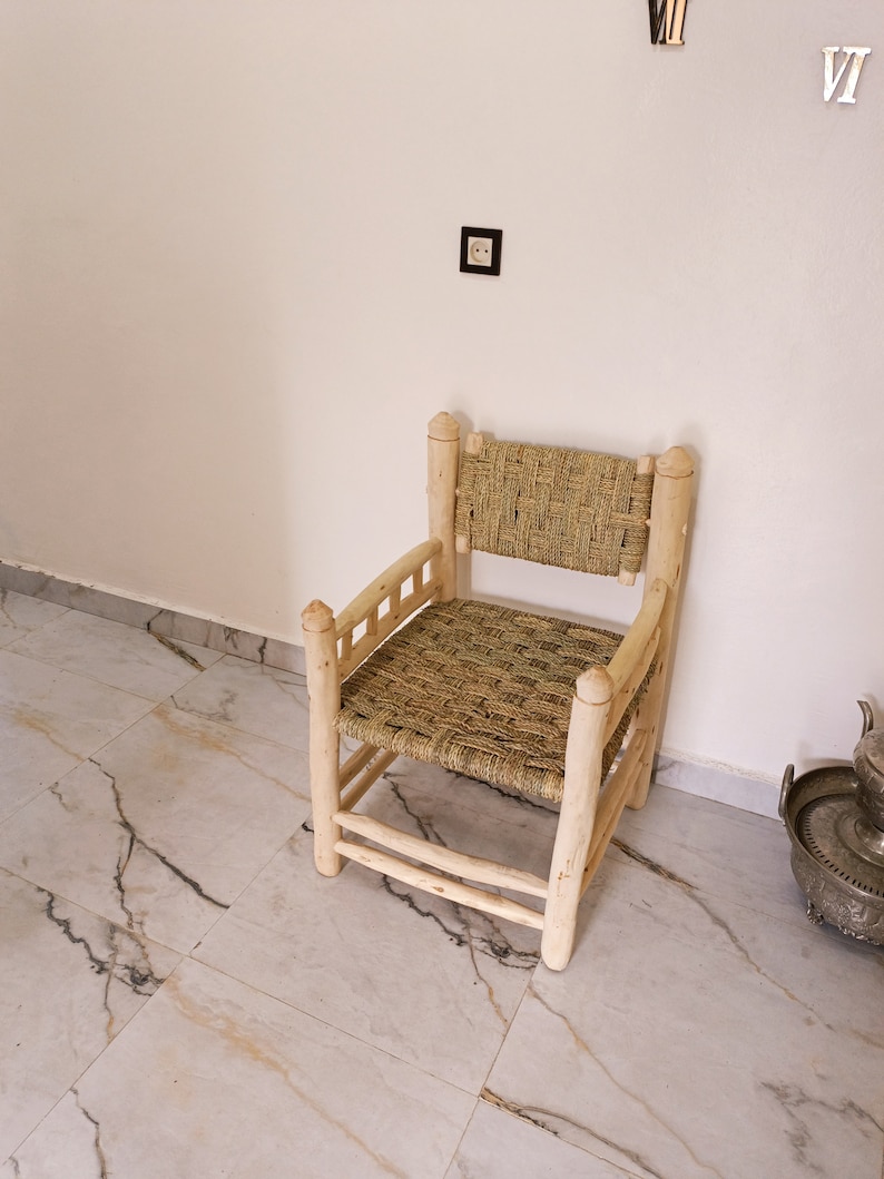 Pode incluir: Uma cadeira de madeira com assento e encosto de vime. A cadeira &eacute; feita de madeira natural e tem um design simples e r&uacute;stico.