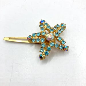 May include: A gold hair clip with a blue rhinestone starfish design.