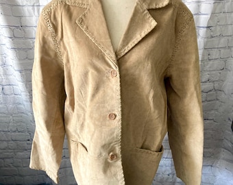 May include: A tan suede blazer with a notched collar, three-button closure, and two front pockets. The jacket features decorative stitching along the seams and edges. The blazer is displayed on a mannequin.