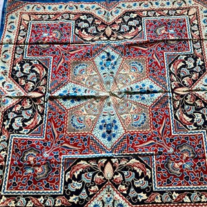 Peut inclure: Un textile carré avec un motif complexe en rouge, bleu, noir et crème. Le motif présente des formes florales et géométriques, avec un motif central en forme d'étoile en bleu clair. Les bords sont bordés d'une bordure bleu foncé.