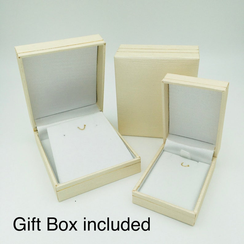 May include: Three cream-colored gift boxes, two open and one closed, with white interiors. The open boxes have a small hook for jewelry. The text "Gift Box included" is at the bottom of the image.