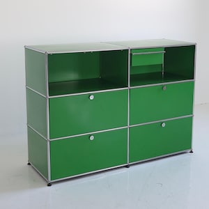 May include: A modular green storage cabinet with a silver frame. The cabinet has open shelves, drawers, and a small pull-out drawer. The cabinet is a vibrant green color and has a modern design.