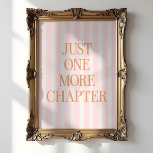 May include: A gold framed picture with a pink and white striped background. The text "JUST ONE MORE CHAPTER" is written in gold letters.