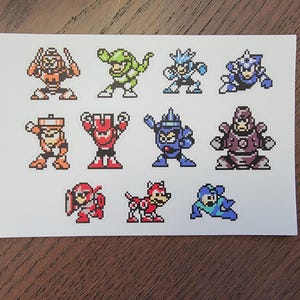 Könnte beinhalten: Ein Set mit 10 Pixel-Art-Aufklebern mit Charakteren aus der Mega Man-Videospielserie. Die Aufkleber sind auf weißem Papier gedruckt und zeigen Charaktere in verschiedenen Posen und Farben, darunter Blau, Rot, Grün und Orange.