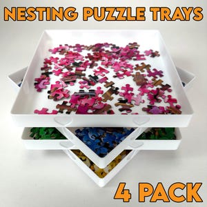May include: Four white nesting puzzle trays with heart-shaped cutouts on the sides. The trays are stacked with puzzle pieces in different colors on each level. The text "4 PACK" is printed in orange at the bottom of the image.
