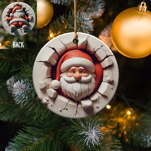 May include: A round white ceramic Christmas bauble with a cracked surface. Santa Claus's face is peeking out of the crack, wearing a red hat and a white beard.