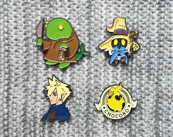 May include: Four enamel pins featuring characters from the Final Fantasy video game series. The pins are on a gray knitted fabric background. The pins depict a green Moogle holding a knife, a black mage wearing a yellow hat, a blonde-haired character with a blue shirt, and a yellow Chocobo with the word "Chocobo" written below it.