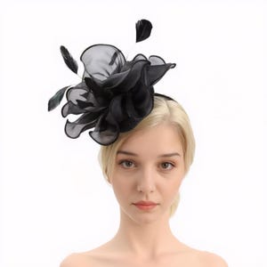 Pode incluir: Um prendedor de cabelo com uma flor preta grande e de v&aacute;rias camadas feita de tecido transparente. A flor &eacute; adornada com pequenas penas pretas.