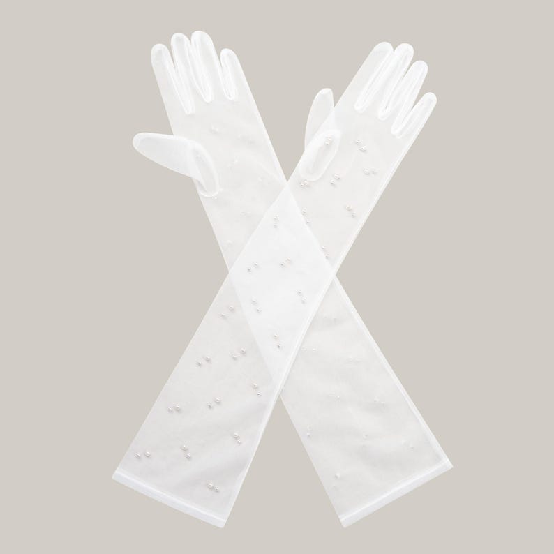 May include: A pair of long white gloves with a delicate pearl pattern. The gloves are made of a sheer fabric and are perfect for a special occasion.