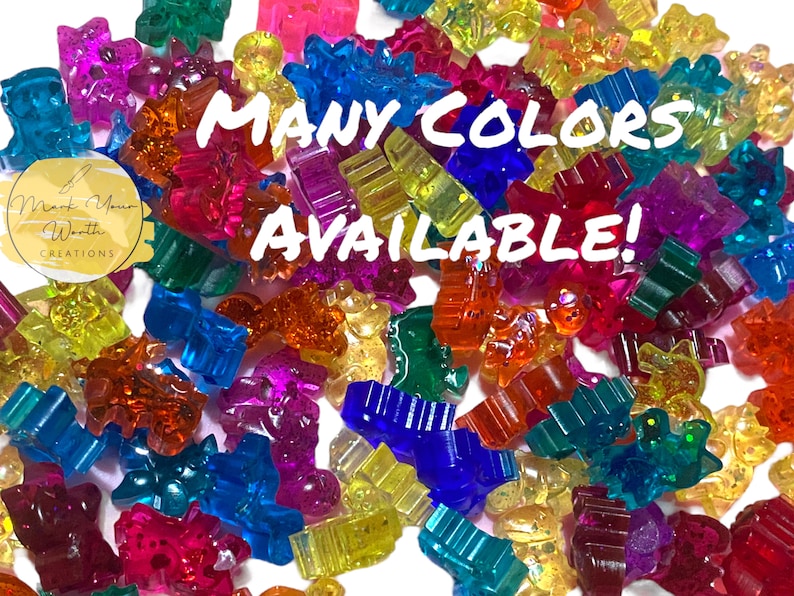 May include: A variety of colourful, glittery, plastic charms in different shapes, including stars, hearts, and animals. The text "MANY COLORS AVAILABLE!" is superimposed on the image.